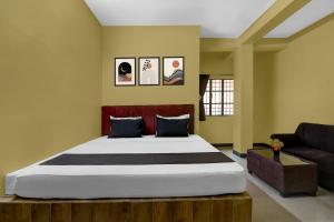 a bedroom with a large bed and a couch at POP 84107A Hotel O J J Lodge in Āsansol +21 photos