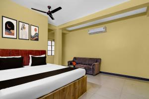 a bedroom with a large bed and a chair at POP 84107A Hotel O J J Lodge in Āsansol