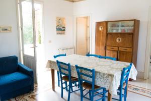 a dining room with a table and blue chairs at Villa Maresole in Favignana