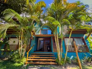 a blue house with palm trees in front of it at Casa no Condomínio Aguas d'Ajuda in Porto Seguro