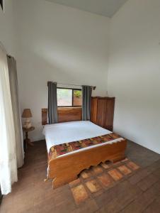 a bedroom with a wooden bed with a window at Villa Piedra Viva in Tilarán