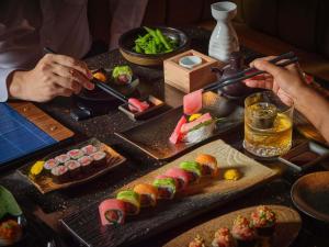 a table topped with sushi and food with people holding chopsticks at Sofitel Bangkok Sukhumvit in Bangkok