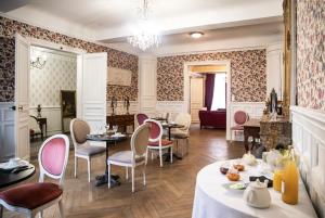 a dining room with tables and chairs and a chandelier at Maison la Louise in Ligny-en-Barrois