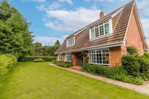 a red brick house with a green yard at Alderfen View by Leap Escapes in Worstead