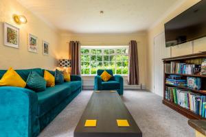 a living room with a blue couch and a book shelf at Alderfen View by Leap Escapes in Worstead