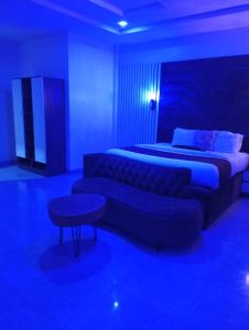 a blue room with two beds and a couch at De Baylux Hotel and Suites, Lekki, Lagos in Maiyegun