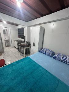 a bedroom with a blue bed and a kitchen at Container Porto Alvorada in Imbituba