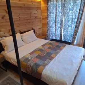a bedroom with a bed with a wooden wall at Casute La Struti in Tîrgu Neamţ