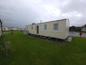 a white trailer sitting in a yard with a grass field at The Retreat Finch - Marine Holiday Park in Rhyl