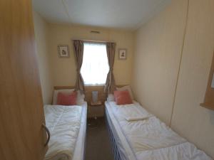 two beds in a small room with a window at The Retreat Finch - Marine Holiday Park in Rhyl +15 photos