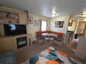 a living room with a television and a table and a couch at The Retreat Finch - Marine Holiday Park in Rhyl