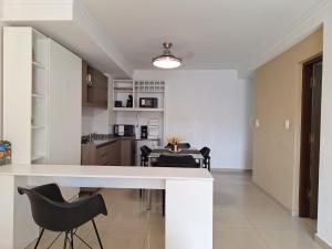 a kitchen with a white counter and black chairs at REFUGIO DEL CENTRO - WiFi 300mbs in Santiago del Estero