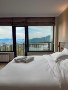 Un dormitorio con una gran cama blanca con grandes ventanales. en Mountain Sky Hotel, 