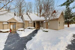 a house covered in snow with a driveway at Newton Village 2B in Quechee