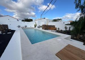 een zwembad voor een wit huis bij Casitas Santa Rita - 2 COSY HOLIDAY HOMES WITH POOL in Guatiza
