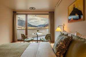 a bedroom with a bed and a table and a window at La Senda Smart Hotel Zuoz in Zuoz
