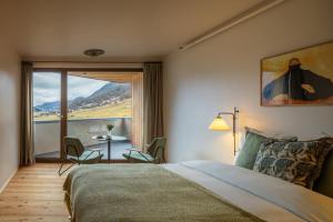 a bedroom with a bed and a table with a view at La Senda Smart Hotel Zuoz in Zuoz