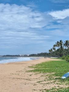 Villa Lanka Rose في Maggona West: شاطئ فيه نخيل والناس تمشي عليه