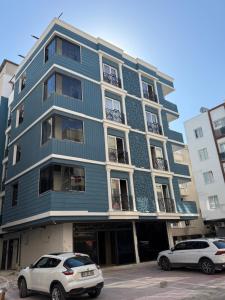 a blue building with two cars parked in front of it at Aljari otel in Mezitli