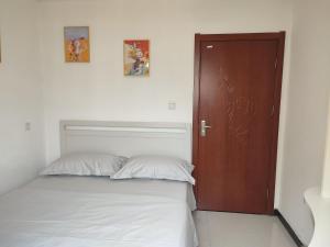ein Schlafzimmer mit einem Bett und einer Holztür in der Unterkunft Jianjia Homestay in Zhengzhou + 2 Fotos