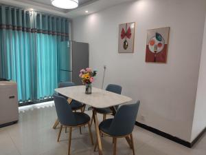 ein Esszimmer mit einem Tisch mit Stühlen und einer Vase aus Blumen in der Unterkunft Jianjia Homestay in Zhengzhou