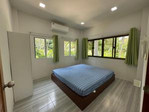 RJJhouse Kohphangan في Ban Nua: غرفة نوم بها سرير ونافذتين