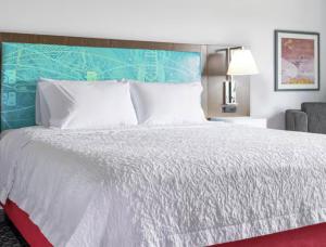 een slaapkamer met een wit bed met een blauw hoofdeinde bij Hampton Inn & Suites Cadillac in Cadillac