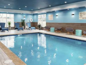 een groot zwembad in een hotellobby met stoelen en tafels bij Hampton Inn & Suites Cadillac in Cadillac