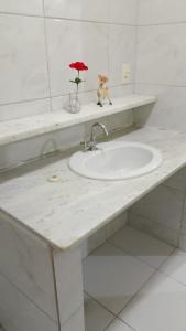 a bathroom counter with a sink and a red umbrella at Casa grande e aconchegante, muito central, aluguel de quartos in Natal