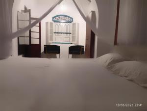 a white bed with two chairs in a room at Grandma's House Villa in Weligama