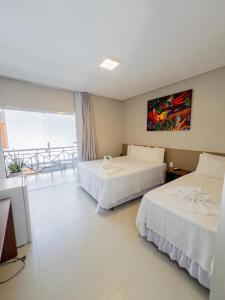 a hotel room with two beds and a window at Charme D'Maria Pousada in Barreirinhas