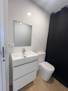 un bagno con lavandino, WC e specchio di Alborada Duplex a Moaña Altre 9 foto