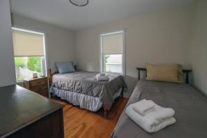 a bedroom with two beds and two windows at Clara's Retreat: Rocky Nook Kingston in Kingston