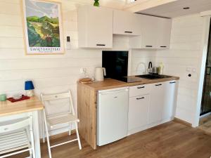 a kitchen with white cabinets and a table and chairs at Jemiołucha Glamp in Bodzentyn +21 photos