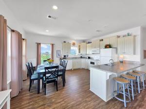 una cucina con tavolo e sedie e una cucina con mobili bianchi di Sea Mist a Gilchrist