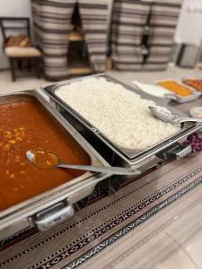 Un buffet con dos bandejas de comida con arroz. en Rum New Luxury Camp, en Wadi Rum