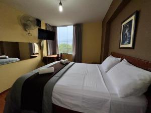 a hotel room with a large white bed with a window at La Posada del Rey - Lima Airport Hostel in Lima