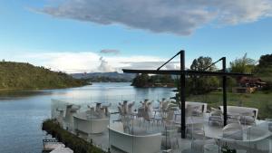 a group of white tables and chairs next to a river at Roka Hotel in Guatapé