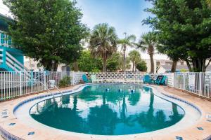 una piscina con sedie blu e alberi di Beachfront Condo w Community Pool a Cape Canaveral