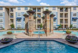 a pool with a fountain in front of a building at Cozy & Chic Frisco Scape in Frisco