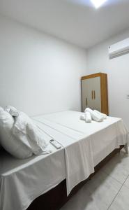a white bed with white sheets and pillows on it at Casa Maroka in Japaratinga