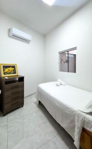 a white bedroom with a bed and a dresser at Casa Maroka in Japaratinga