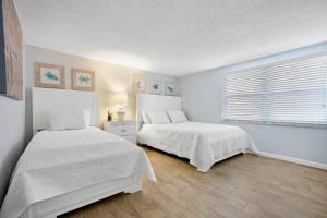 een slaapkamer met twee bedden en een raam bij Cocoa Beach Club-Beachfront Condo in Cape Canaveral