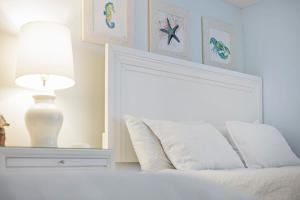 een slaapkamer met een bed met een lamp en foto's aan de muur bij Cocoa Beach Club-Beachfront Condo in Cape Canaveral +30 foto's