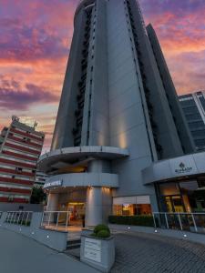 a large building with a sunset in the background at Mercure Nações Unidas - Apto 910 in Sao Paulo