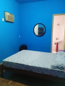 Hotel Flamingo's في سانتوس: غرفة نوم زرقاء مع سرير ومرآة +صورة واحدة