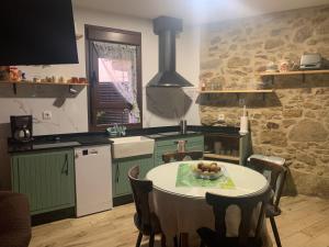 CASA RURAL PUERTO-Ideal para disfrutar en familia في Casas del Monte: مطبخ مع طاولة ومطبخ مع جدار حجري
