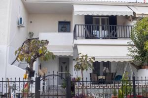 a white house with a balcony and a fence at Lithaia Aura-Trikala in Pýrgos