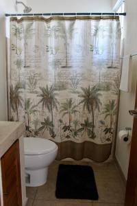 a bathroom with a shower curtain with palm trees at Terraza Carrizalillo in Puerto Escondido