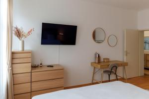 a bedroom with a bed and a desk and a tv on the wall at Gemütliche 2-Raum-Wohnung in Leipzig